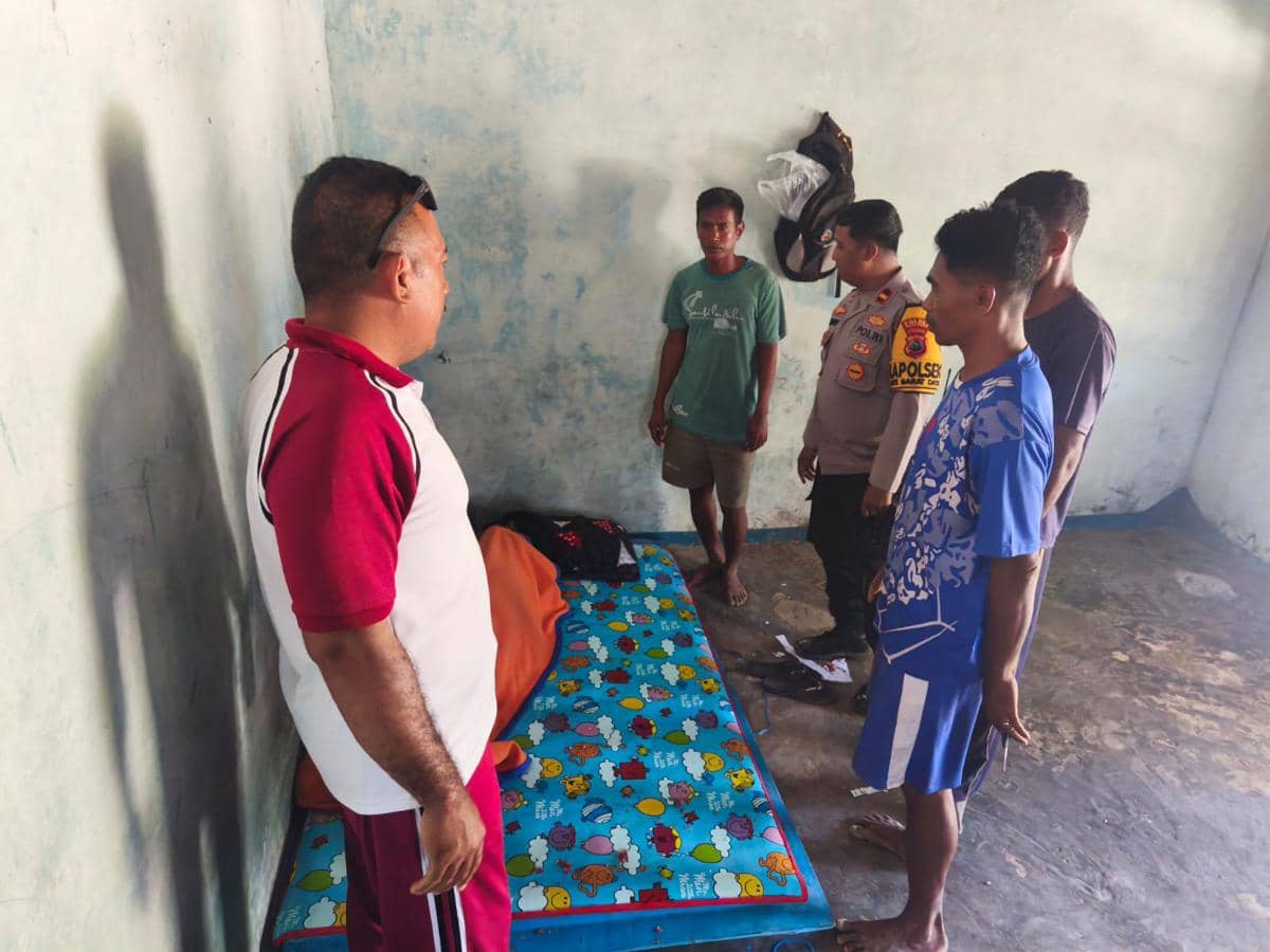 Petugas Polsek Rote Barat Daya bersama warga meninjau kondisi korban kapal tenggelam di sebuah ruangan sederhana dengan kasur di lantai.