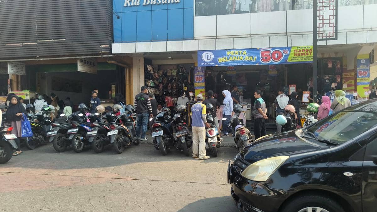 Deretan sepeda motor terparkir di depan toko Ria Busana di Jalan Surya Kencana, Kota Bogor, dengan beberapa orang berbelanja.