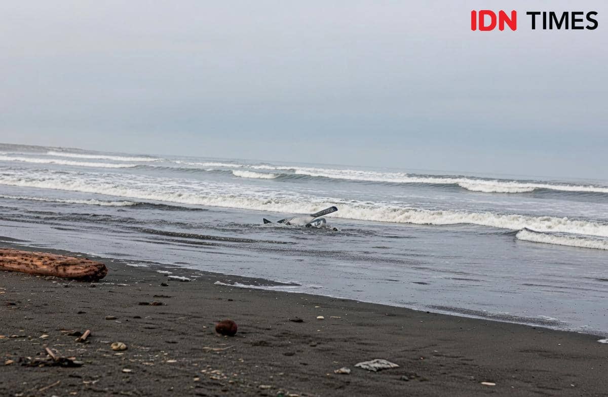 Pantai Bleberan di kawasan Pantai Bunton Adipala dengan ombak besar dan puing-puing di tepi pantai pada hari berawan.