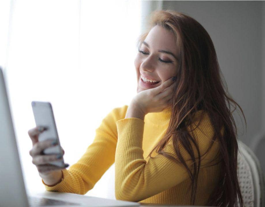 Wanita Tersenyum Menatap Ponsel 