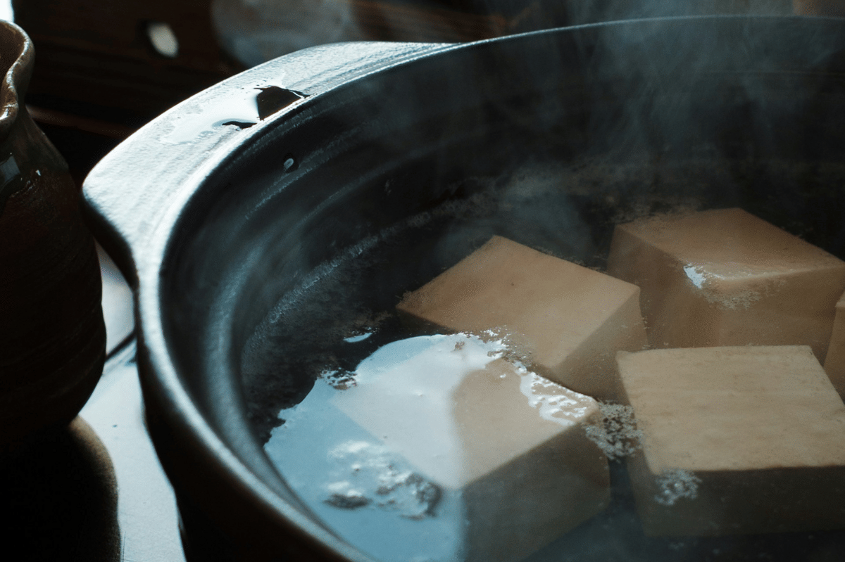 Pot berisi potongan tahu yang sedang direbus dalam air panas dengan uap mengepul, sebagai langkah awal membuat mapo tofu don.
