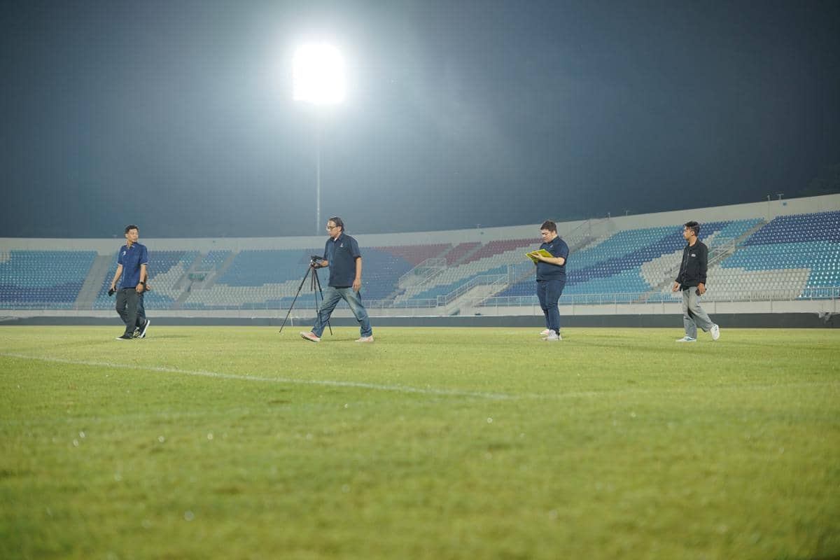 Tim verifikator ILeague berjalan di lapangan Stadion Kanjuruhan saat melakukan inspeksi di bawah pencahayaan stadion pada malam hari.