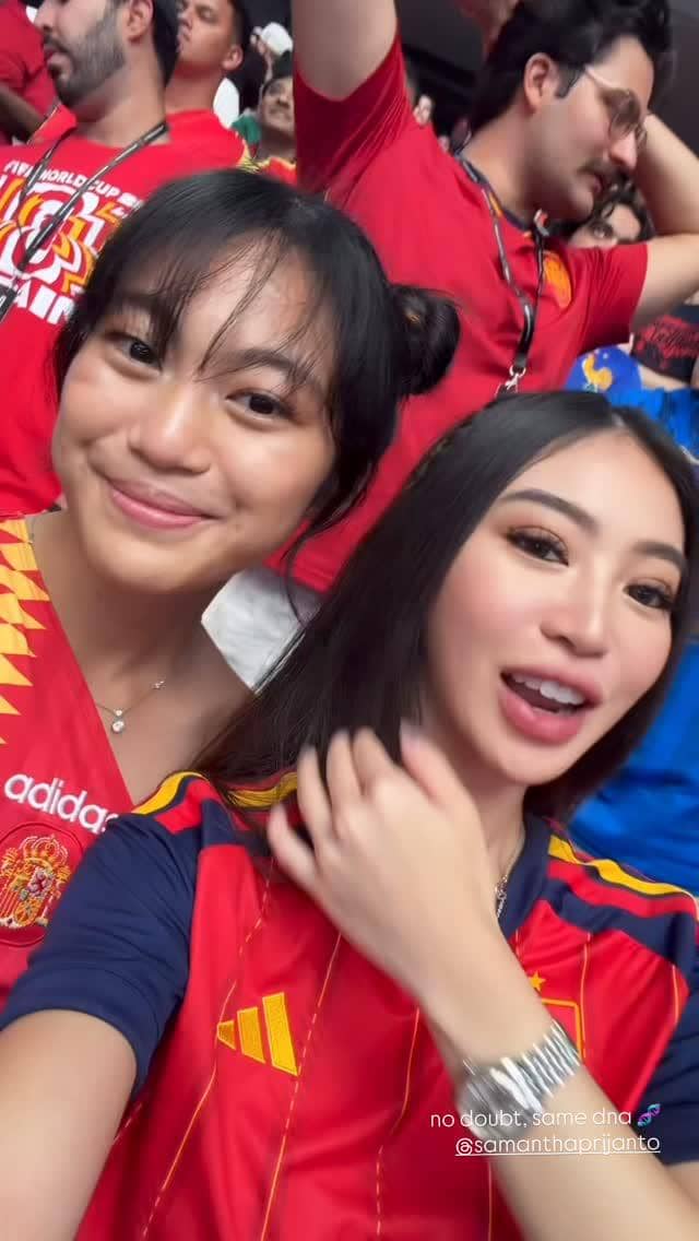 Dua perempuan mengenakan jersey tim nasional Spanyol berfoto selfie di tribun stadion saat menonton pertandingan Spanyol versus Prancis.