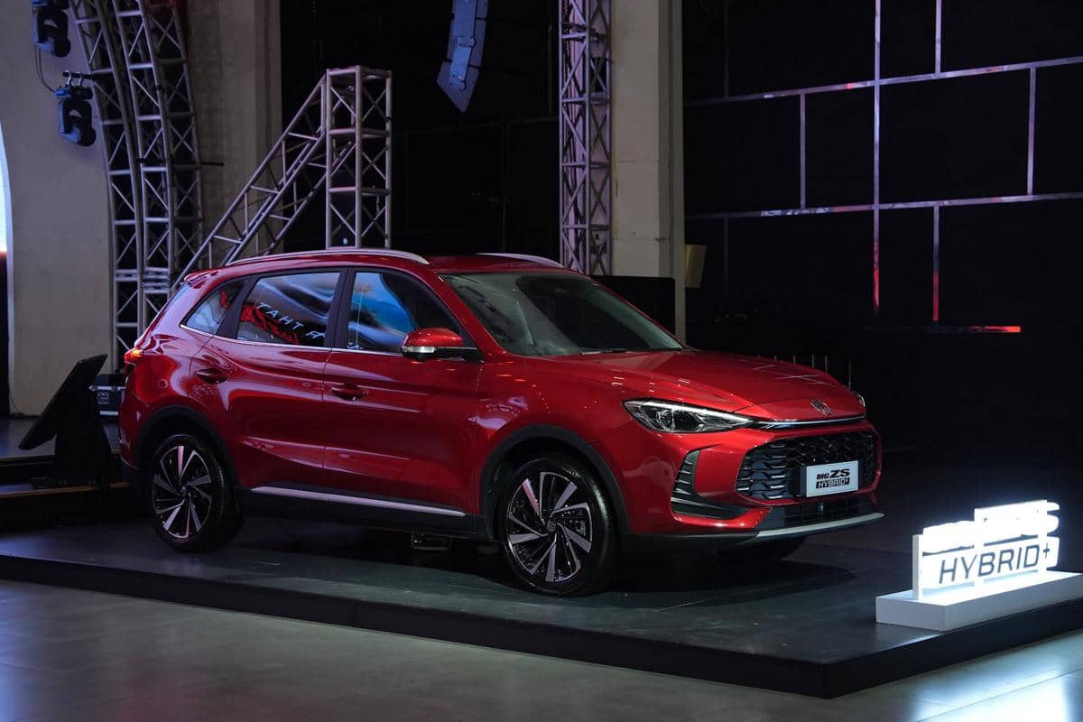 Mobil MG ZS Hybrid+ berwarna merah dipamerkan di atas panggung dengan pencahayaan studio dan latar belakang gelap.
