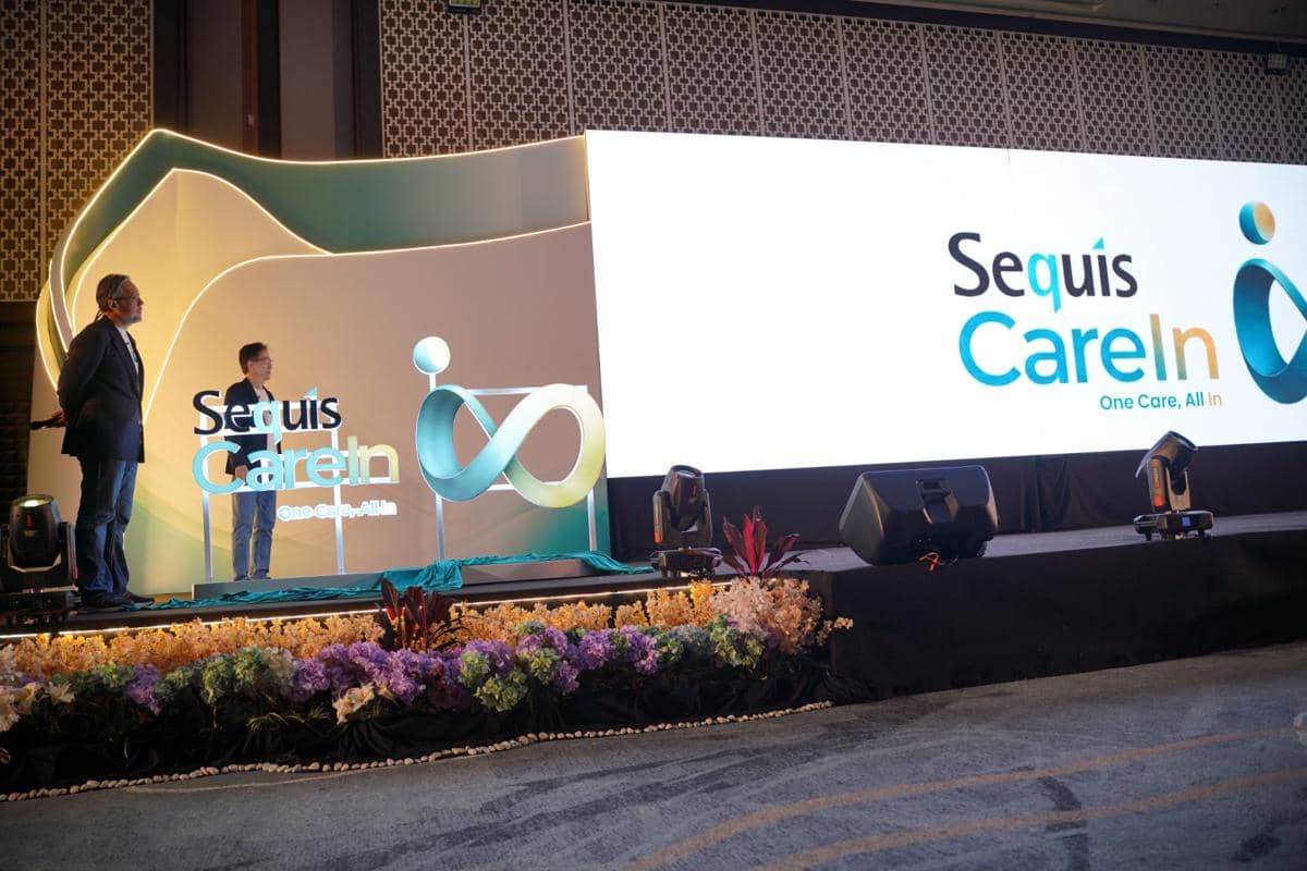 Dua eksekutif Sequis Life berdiri di atas panggung saat peluncuran Sequis CareIn dengan konsep One Care, All In di sebuah acara resmi.
