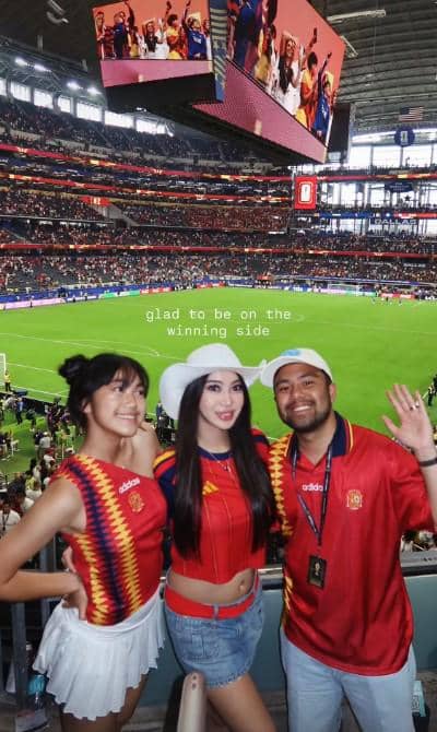 Tiga orang mengenakan jersey tim nasional Spanyol berpose di stadion besar saat pertandingan Spanyol melawan Prancis berlangsung.
