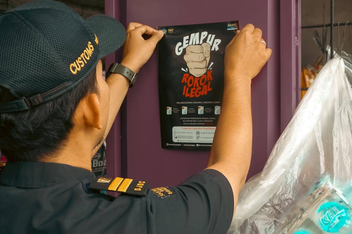 Petugas Bea dan Cukai Sumbagbar memasang poster kampanye bertuliskan 'Gempur Rokok Ilegal' di dinding berwarna ungu sebagai bagian dari kegiatan penertiban.