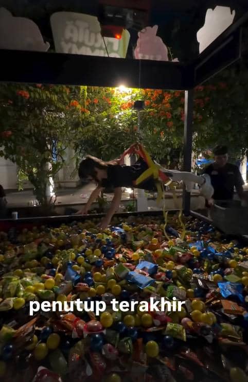 Seorang tamu artis mengenakan tali pengaman bermain di wahana capit manusia berisi bola dan camilan saat ulang tahun ke-6 Gala Sky.