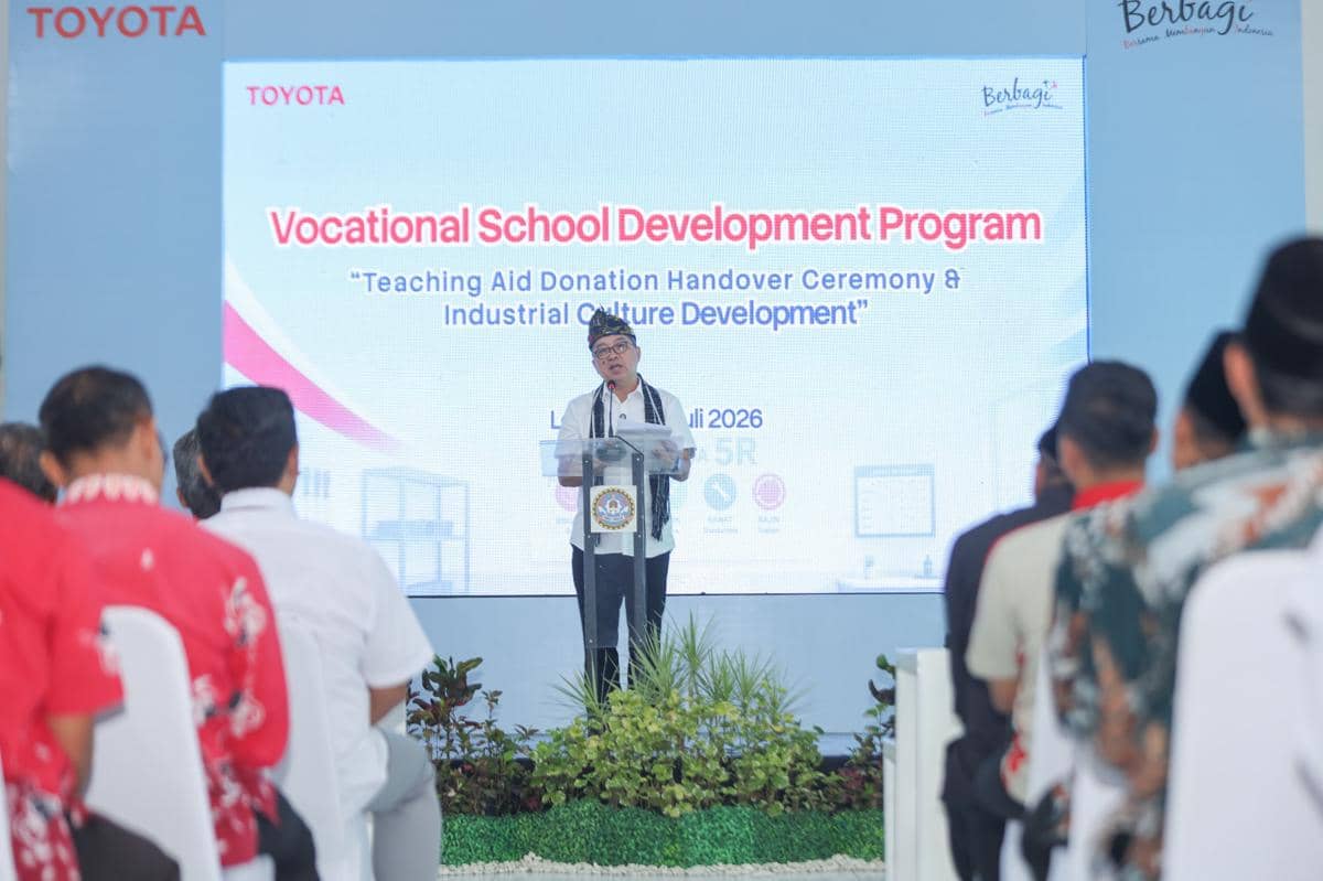 Seorang pembicara berdiri di podium memberikan sambutan pada acara Vocational School Development Program yang dihadiri sejumlah peserta.