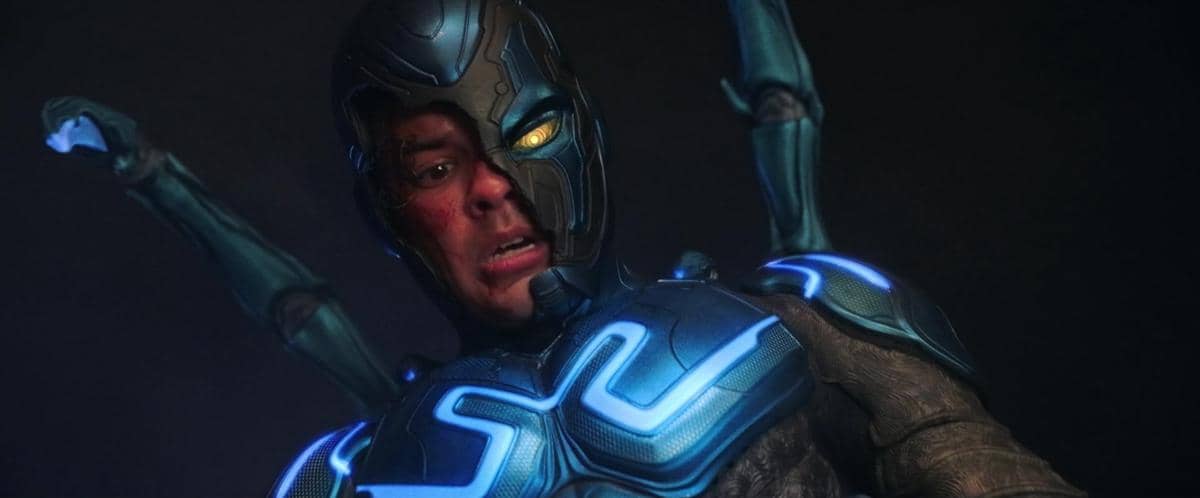 Seorang karakter mengenakan kostum futuristik berwarna biru dengan cahaya neon dan ekspresi tegang dalam adegan film Blue Beetle.