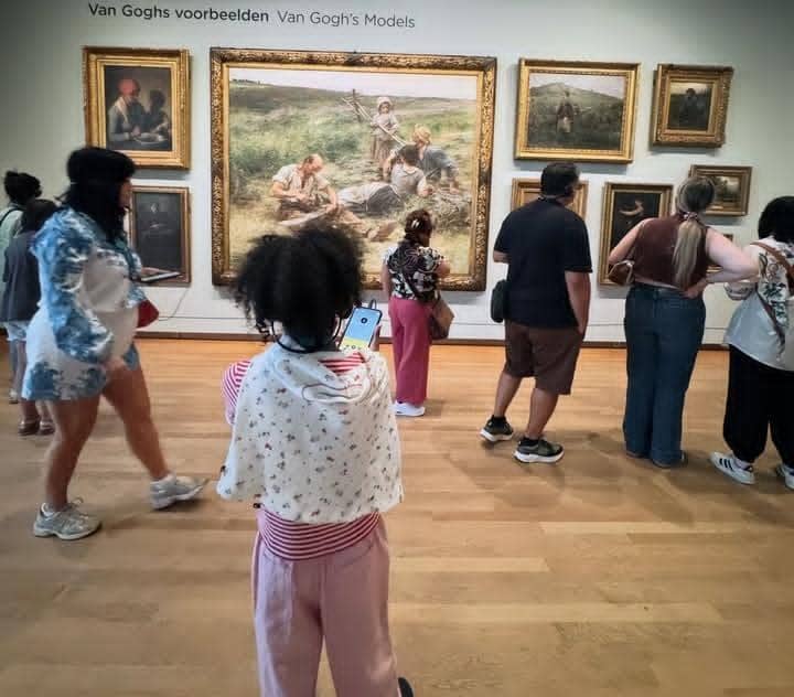 Seorang anak dan beberapa pengunjung melihat lukisan karya Van Gogh di ruang pamer Museum Van Gogh dengan dinding penuh karya seni berbingkai emas.