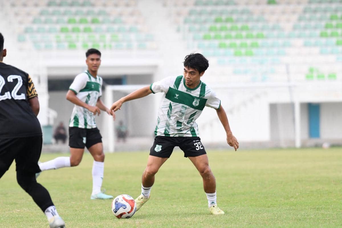 Pemain PSMS mengontrol bola saat pertandingan melawan Muspika FC di Stadion Min Pancing dengan latar tribun kosong.
