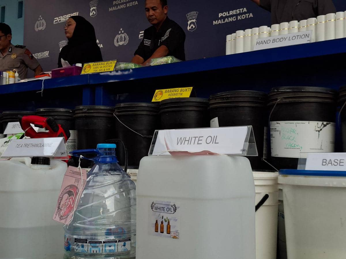 Barang bukti bahan kimia dan kosmetik ilegal ditampilkan di meja konferensi pers Polresta Malang Kota bersama beberapa petugas kepolisian.