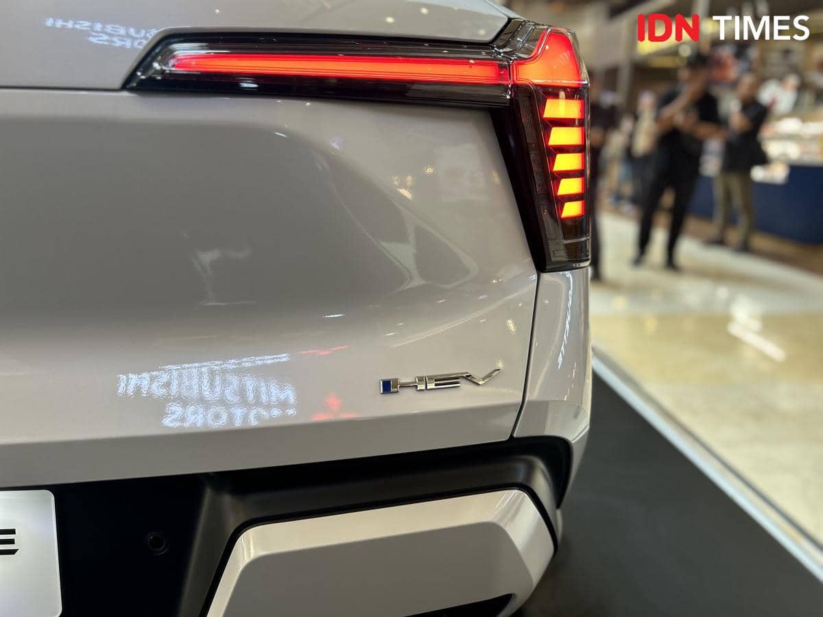 Tampak belakang mobil New Xforce berwarna abu-abu dengan emblem HEV di pintu bagasi dan lampu belakang menyala merah.