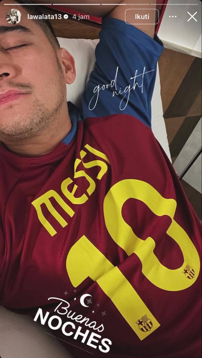 Seorang pria berbaring sambil mengenakan jersey bertuliskan nama Messi dan nomor 10 dengan tulisan 'good night' di atasnya.