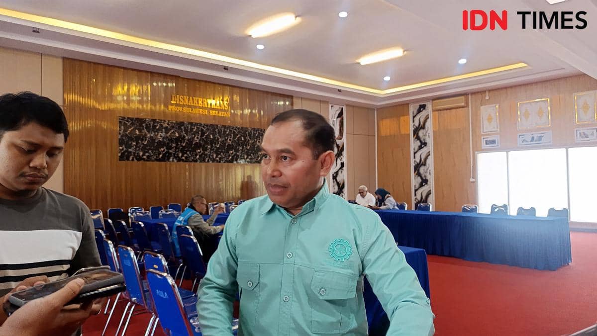 Seorang pria berbaju hijau berbicara dengan wartawan di ruang rapat Dinas Tenaga Kerja dan Transmigrasi Provinsi Sulawesi Selatan.