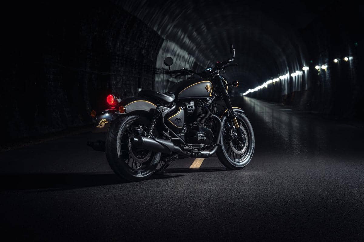 Motor Royal Enfield edisi spesial berwarna hitam dengan aksen emas diparkir di dalam terowongan dengan pencahayaan redup.