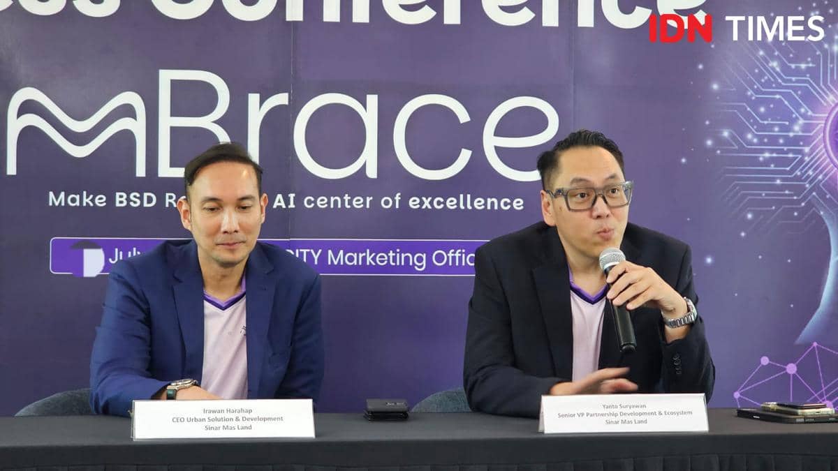 Dua pria berbicara dalam konferensi pers peluncuran mBrace di BSD City dengan latar belakang ungu bertuliskan mBrace.
