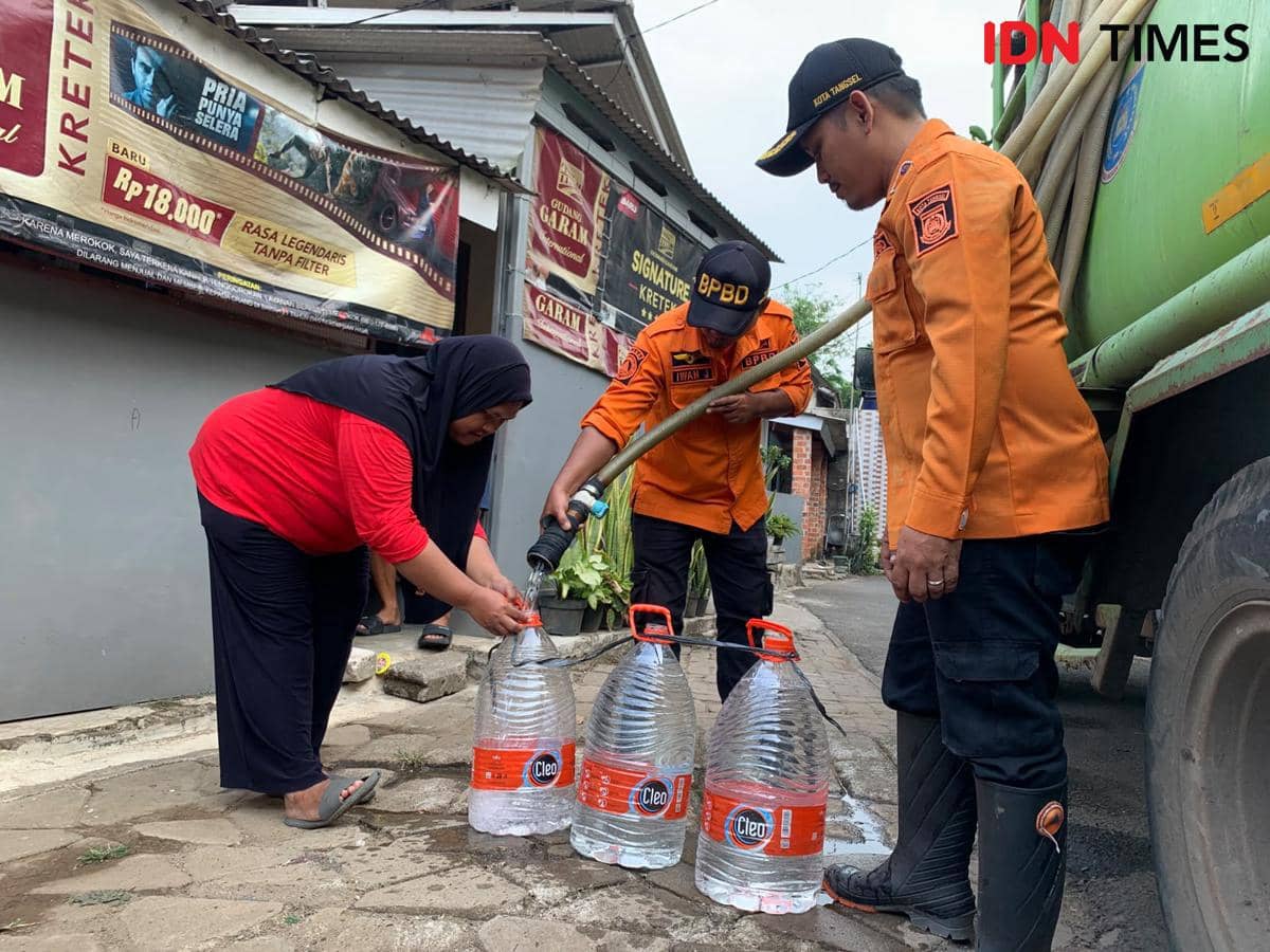 Petugas BPBD Tangsel menyalurkan air bersih kepada warga yang terdampak kekeringan menggunakan truk tangki di kawasan pemukiman.