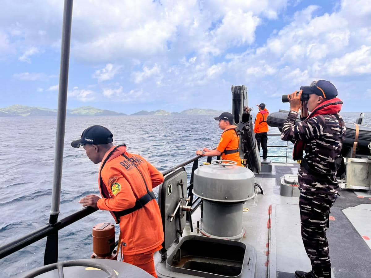 Petugas Basarnas dan aparat berseragam melakukan pencarian penumpang kapal tenggelam di perairan Selayar dari atas kapal di laut.