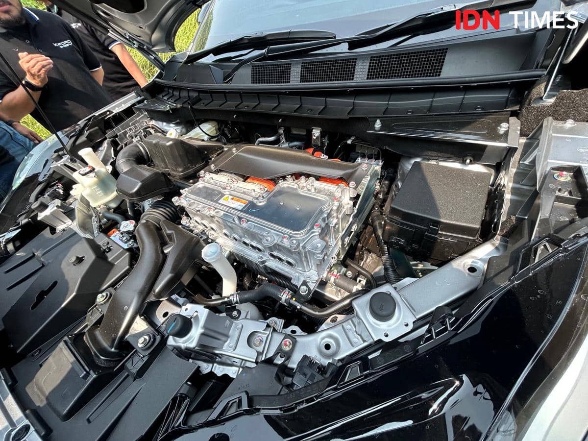 Ruang mesin Mitsubishi New Xforce Hybrid dengan komponen mesin dan sistem kelistrikan terlihat jelas saat kap mobil terbuka.