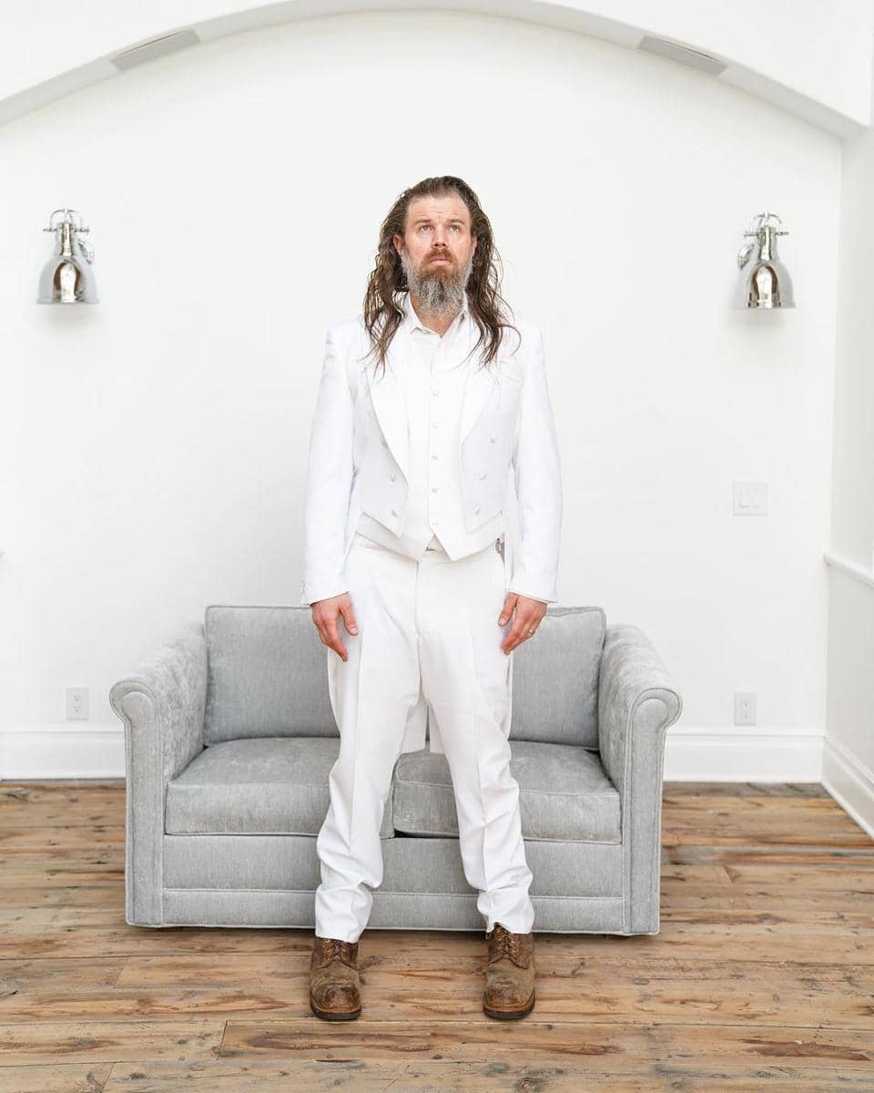 Ryan Hurst berdiri dengan mengenakan setelah serba warna putih