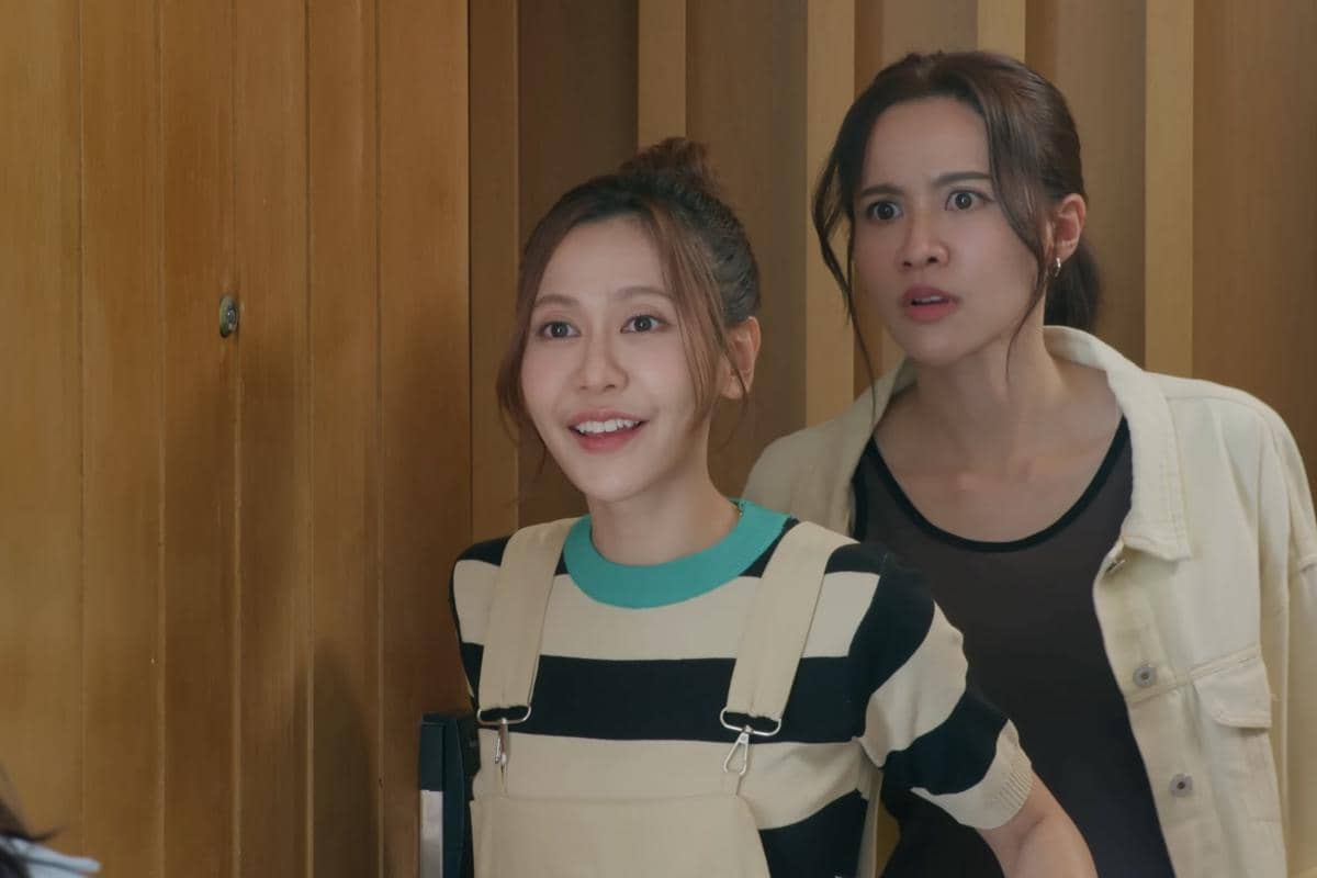Dua perempuan berdiri di depan pintu kayu, satu tersenyum cerah sementara yang lain tampak terkejut dalam adegan drama The Fire.