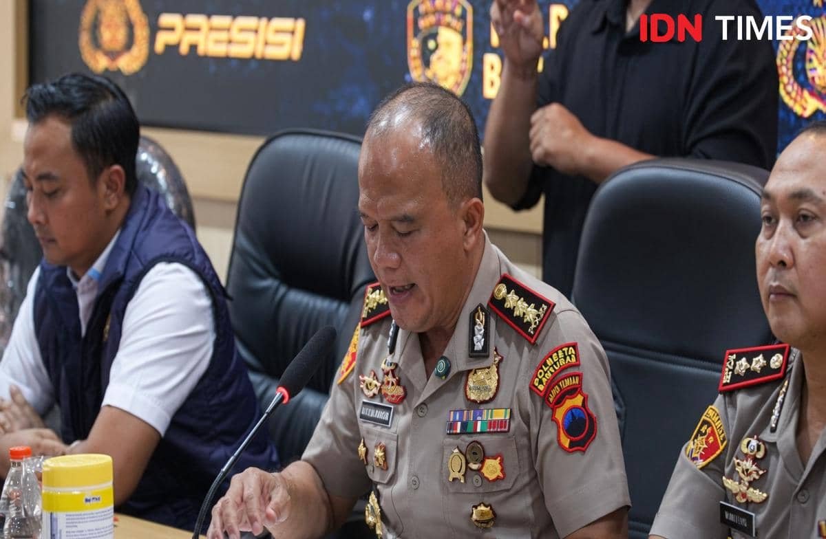 Seorang perwira polisi berpakaian dinas tengah berbicara di depan mikrofon dalam konferensi pers bersama beberapa anggota kepolisian lainnya.