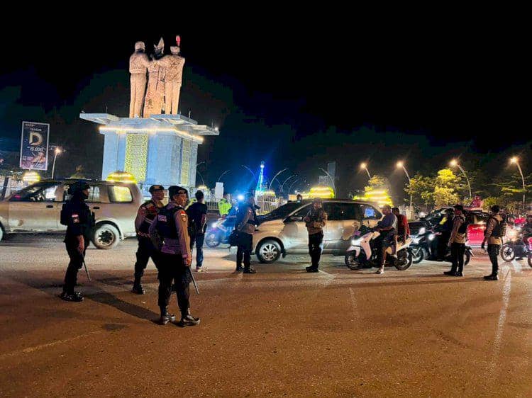 Personel polisi berjaga di jalan Kota Kupang saat mengamankan konvoi Tahun Baru 2026 di sekitar area tugu pada malam hari.