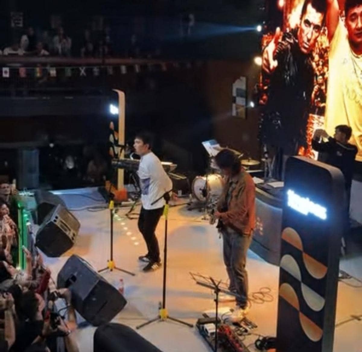 Penampilan musik live di Bajawa Medan dengan penyanyi dan gitaris di atas panggung di depan penonton yang antusias.