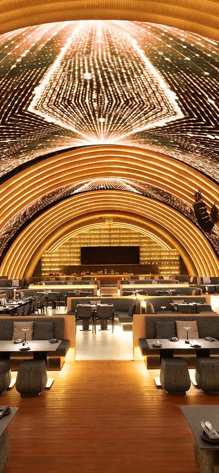 Interior restoran Black Owl dengan desain lengkung futuristik dan pencahayaan hangat berwarna keemasan di langit-langit.