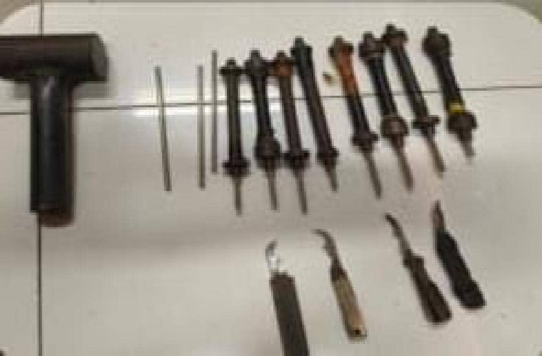Deretan alat bukti berupa beberapa batang logam, obeng, dan alat tajam sederhana yang disita polisi di atas permukaan putih.