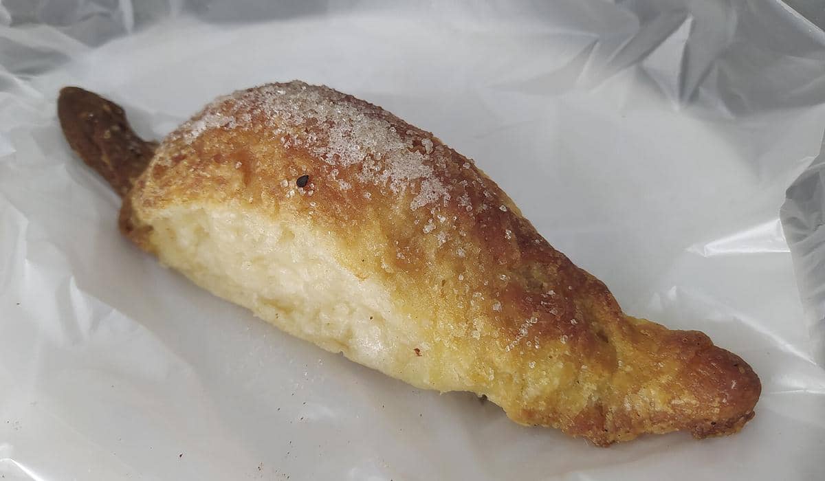 Roti vigilante berlapis gula dengan tekstur renyah keemasan di atas permukaan, diletakkan di atas alas plastik putih.