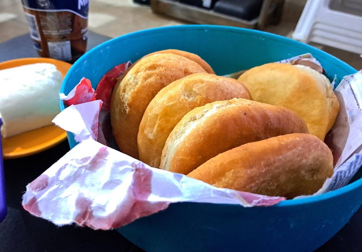 Beberapa tortas fritas berwarna keemasan tersusun dalam mangkuk biru dengan alas kertas, siap disajikan sebagai camilan.