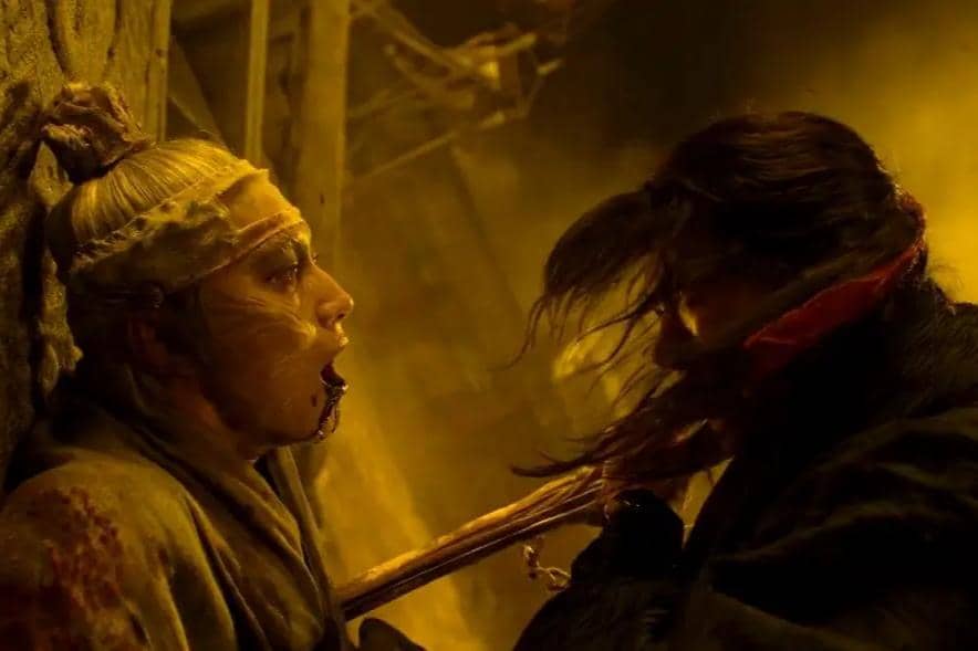 Adegan intens dua karakter dalam drama The East Palace, satu karakter terluka parah sementara lainnya memegang senjata di latar gelap kekuningan.