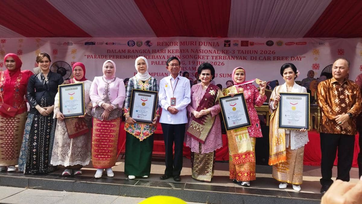 Sejumlah perempuan mengenakan kebaya dan kain songket berpose bersama piagam rekor MURI dalam acara Parade Kebaya Songket di Palembang.