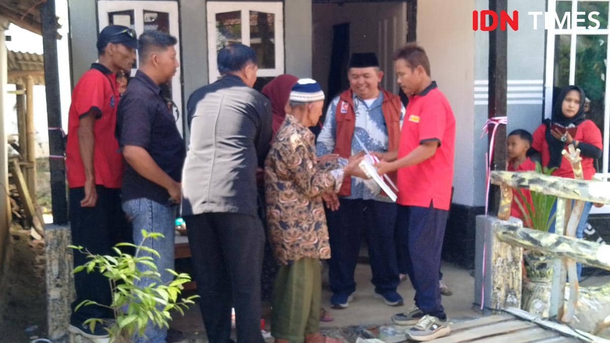 Beberapa orang berdiri di depan rumah sederhana saat penyerahan kunci rumah kepada seorang pria lanjut usia di Banyumas.