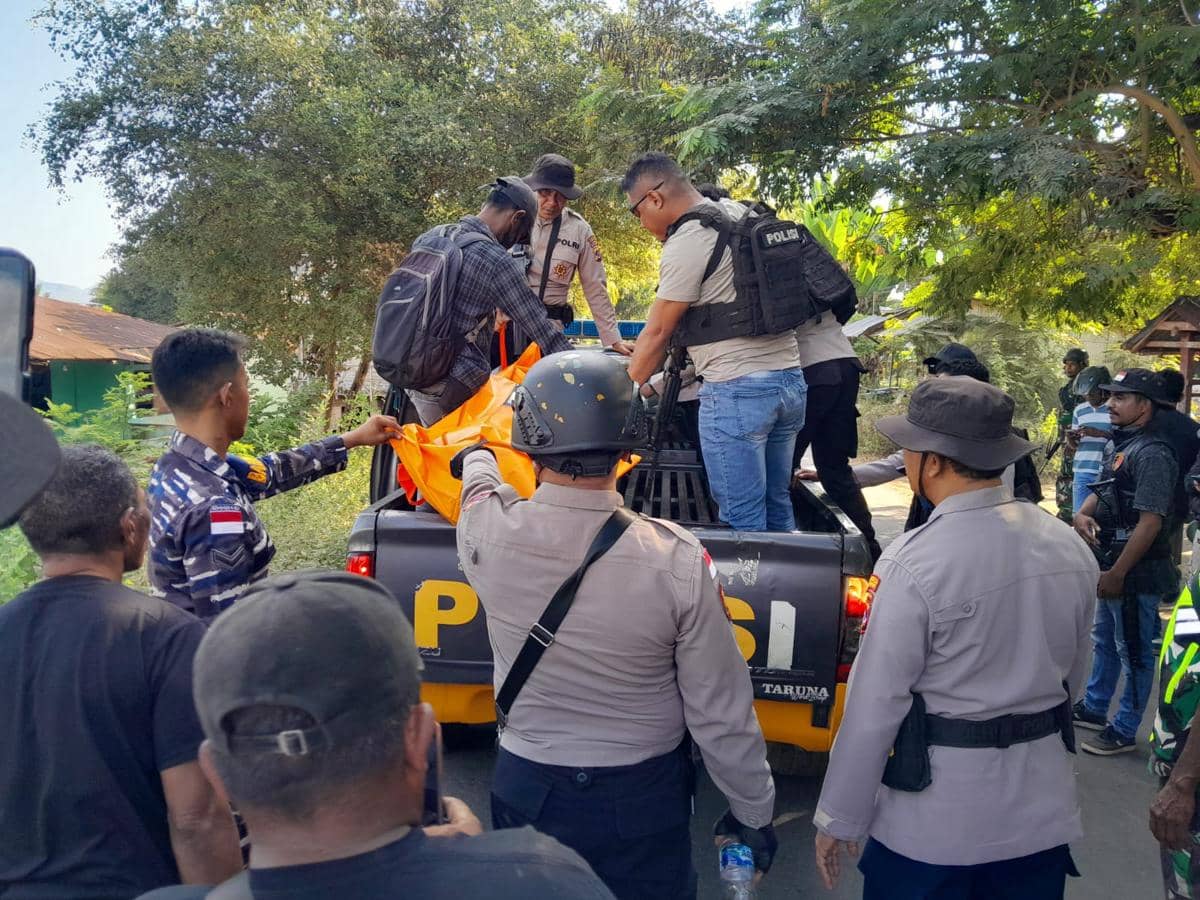 Petugas kepolisian mengevakuasi jenazah korban konflik ke atas mobil polisi di Adonara Timur, disaksikan sejumlah warga di lokasi.