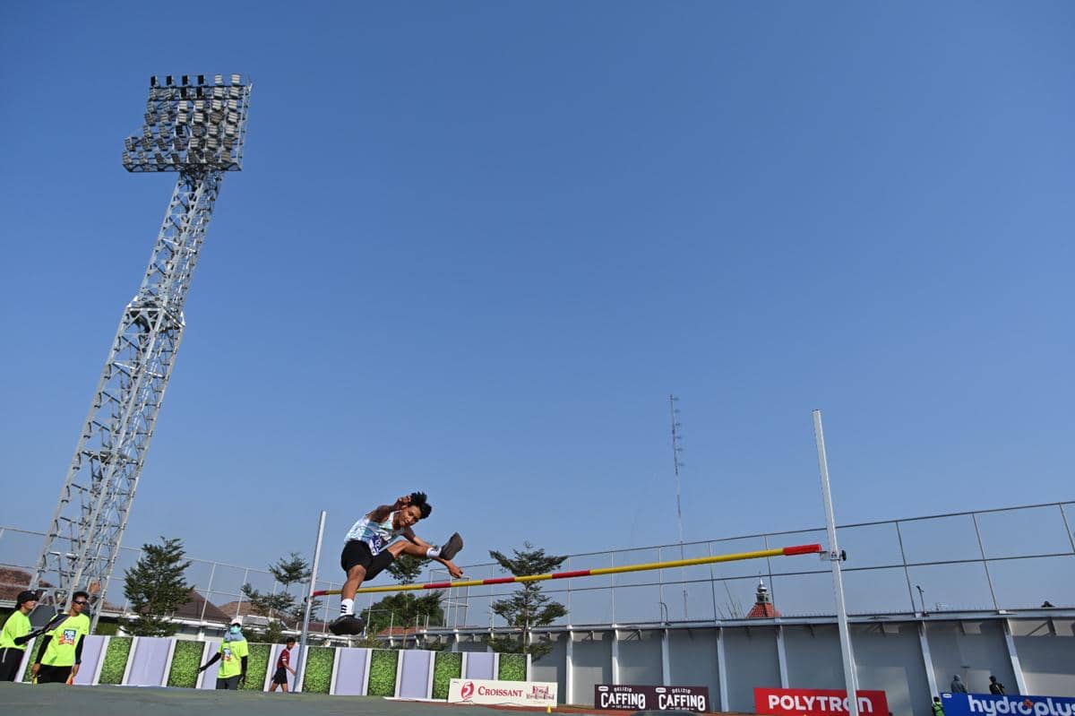 Seorang atlet melompat tinggi melewati mistar pada ajang MilkLife Athletics Challenge Seri 1 2026 di stadion terbuka dengan langit cerah.