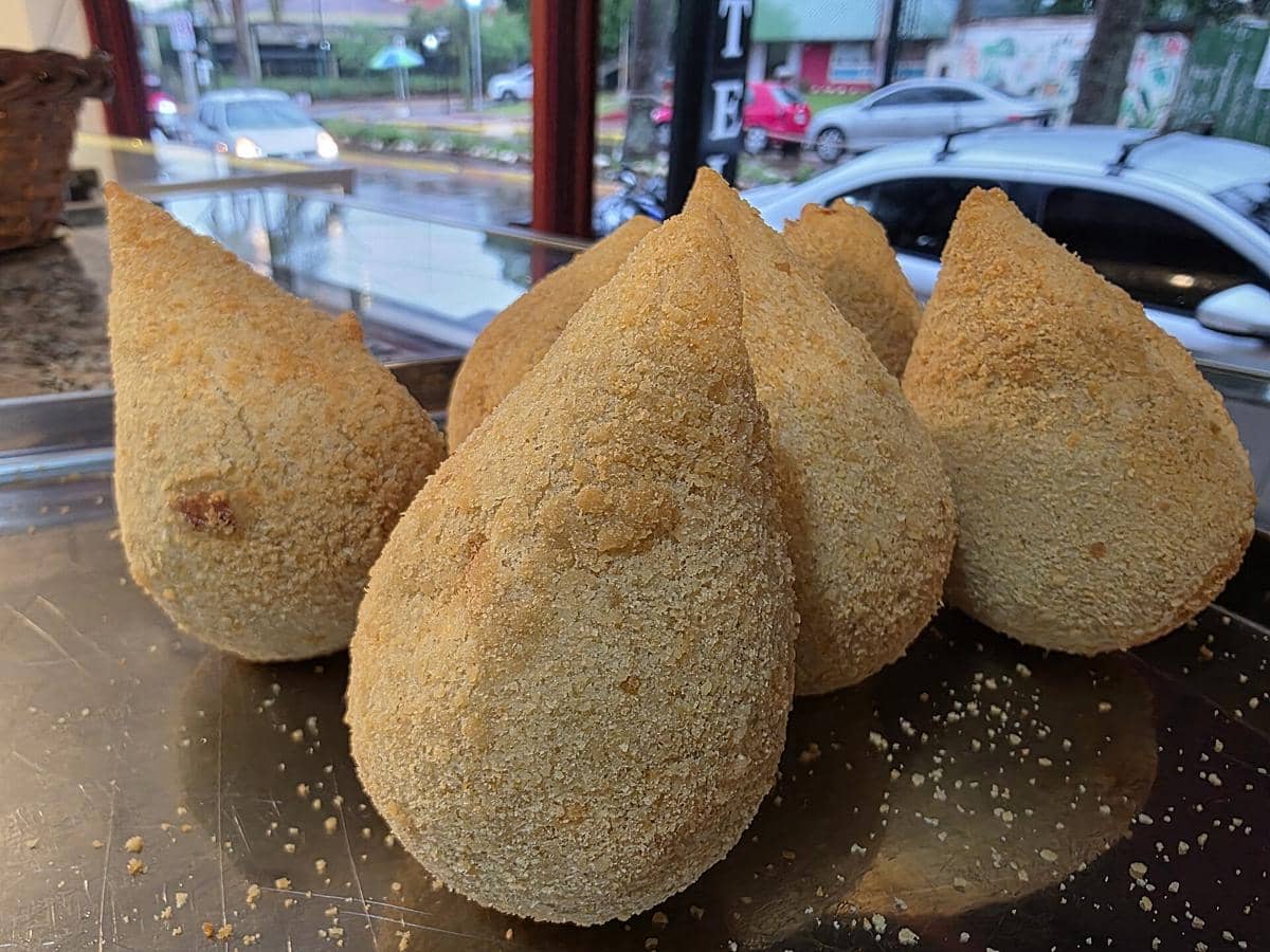 Ilustrasi coxinha, camilan goreng khas Brasil berbentuk paha ayam dengan lapisan renyah berwarna keemasan.