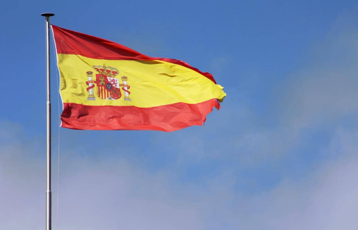 Bendera Spanyol berkibar di tiang dengan latar langit biru