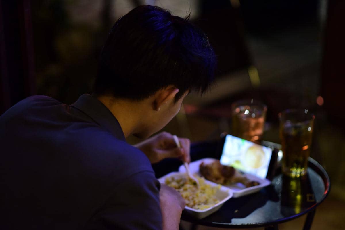 Ilustrasi laki-laki sedang makan sambil menonton video mukbang