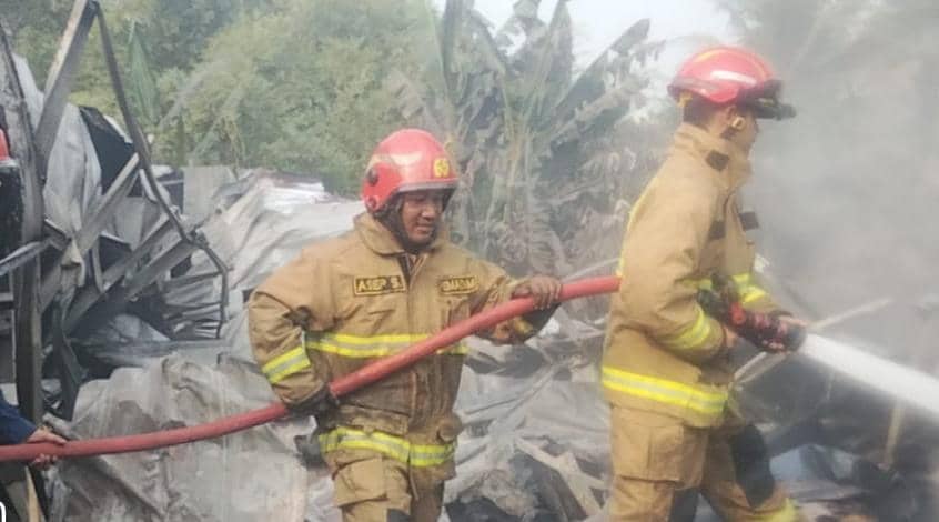 Petugas pemadam kebakaran memadamkan api di gudang sparepart motor yang terbakar di Bogor dengan menggunakan selang air.