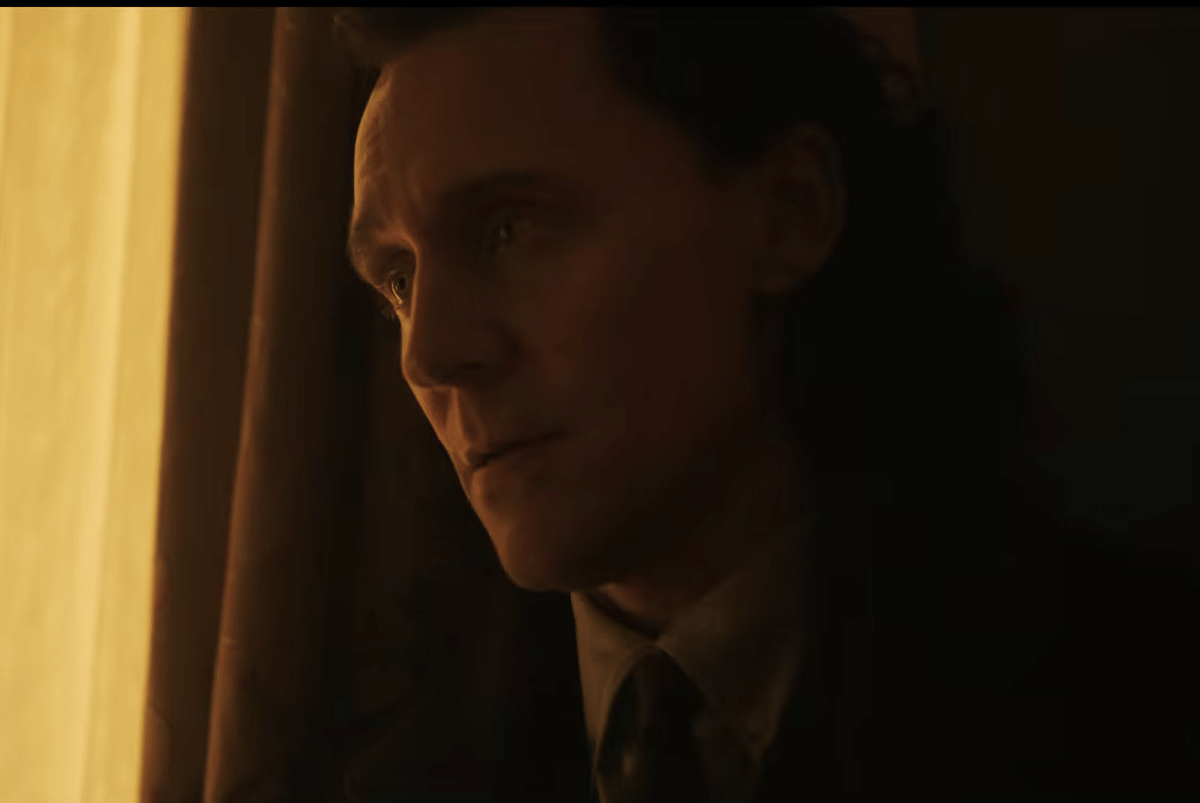 Loki mengenakan jas gelap dan dasi, berdiri di dekat jendela dengan pencahayaan hangat dalam cuplikan trailer Avengers: Doomsday.