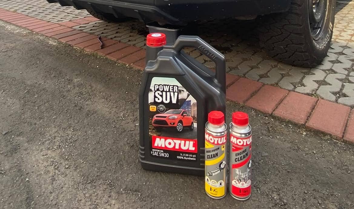 Produk aditif Motul untuk B50 terdiri dari oli mesin Power SUV SAE 5W30 dan dua botol pembersih sistem bahan bakar di dekat mobil.