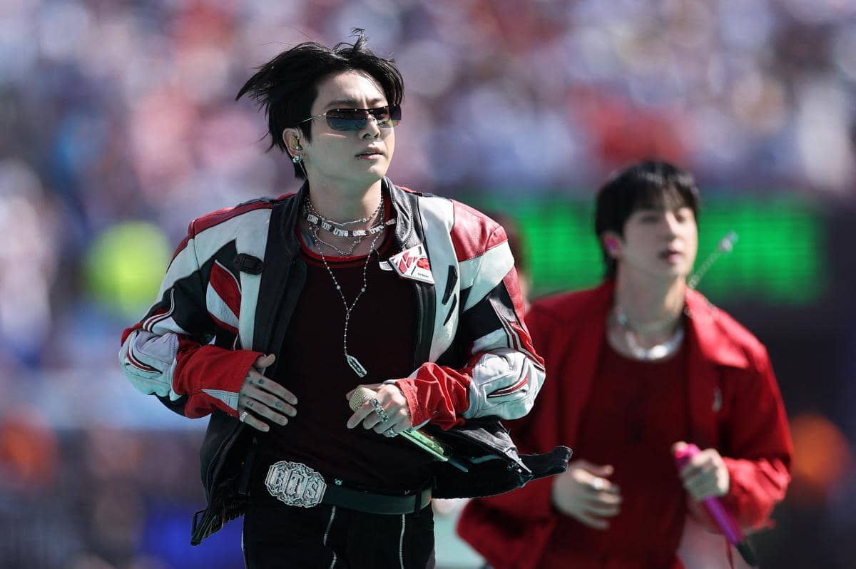Seorang anggota BTS mengenakan jaket kulit merah hitam tampil energik di panggung Half Time Show Piala Dunia 2026.