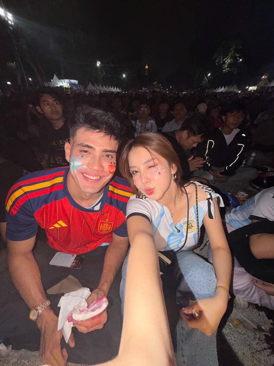 Dua orang mengenakan jersey tim nasional Spanyol dan Argentina berfoto selfie di tengah keramaian acara nonton bareng final Piala Dunia 2026.