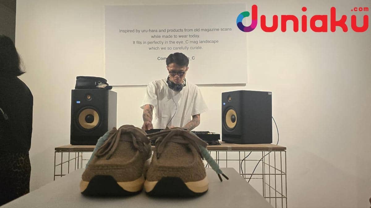 Seorang DJ memainkan musik di acara peluncuran sepatu SEA Velocity Moc edisi kolaborasi COMPASS x eye_C dengan latar dinding putih.