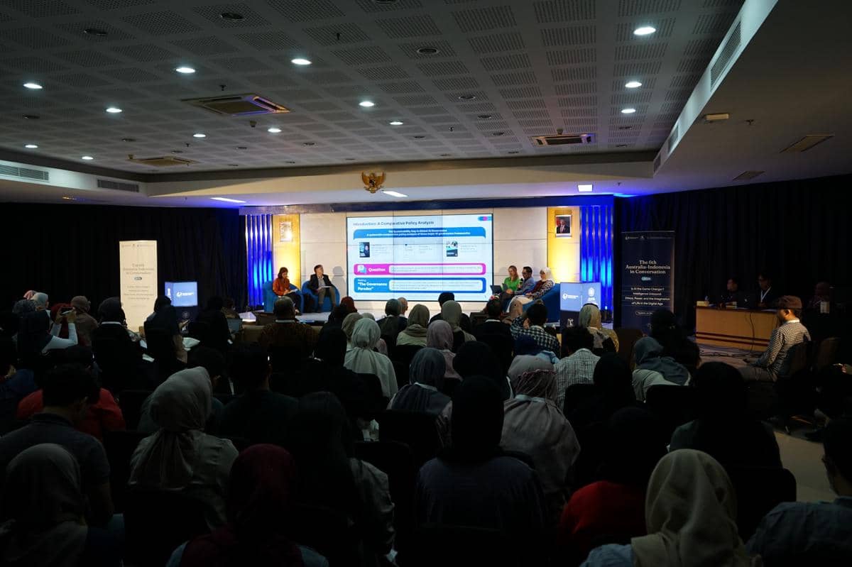 Suasana forum The 6th Australia–Indonesia in Conversation 2026 di FISIPOL UGM dengan peserta memenuhi ruangan dan panelis di atas panggung.