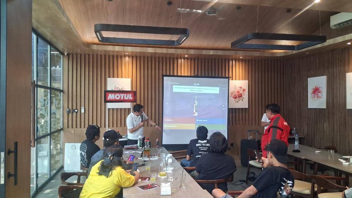 Perwakilan Motul memberikan presentasi di depan distributor dan bengkel dalam ruangan dengan layar proyektor dan dekorasi kayu modern.